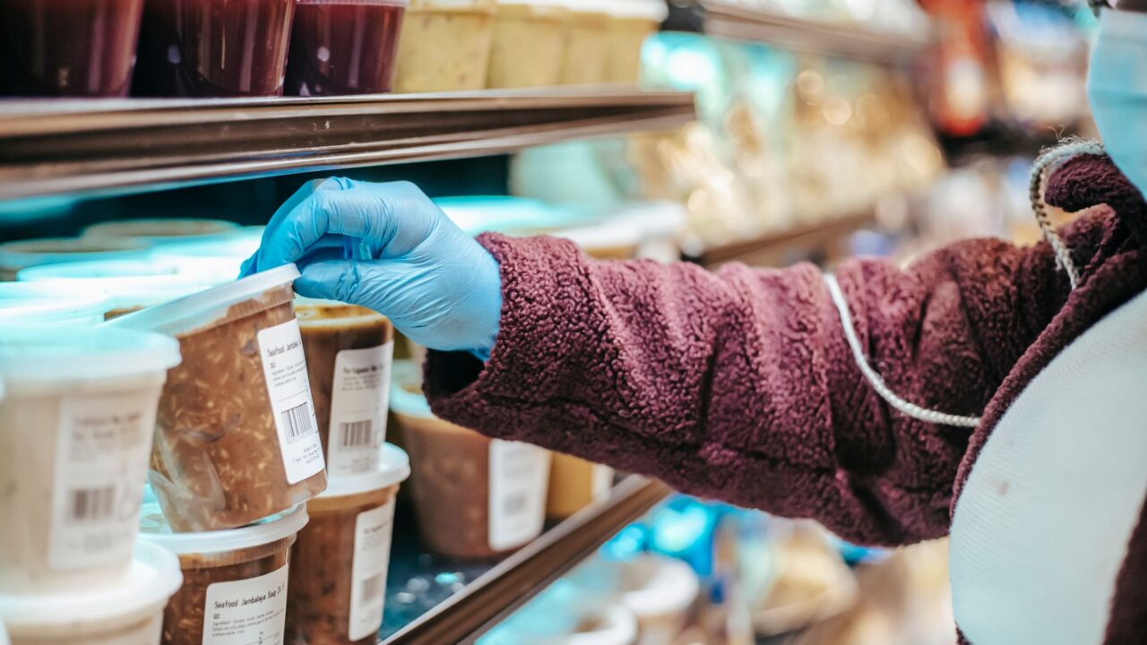 Persoană care citește eticheta unui produs alimentar într-un supermarket